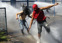 Jóvenes se enfrentan a la policía en una marcha estudiantil convocada por las principales asociaciones estudiantiles en favor de la educación, este 28 de marzo, en Santiago. EFE