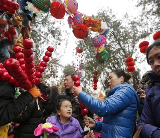 Una familia compra juguetes y recuerdos en un puesto en una feria en el segundo día del Año Nuevo Lunar, en el Festival de Primavera en Pekín, China. EFE