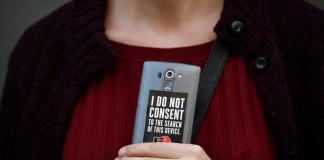 Una mujer sostiene su teléfono móvil en el que aparece una pegatina en la que se puede leer "No consiento la inspección de este móvil" durante una manifestación frente a una tienda Apple. EFE